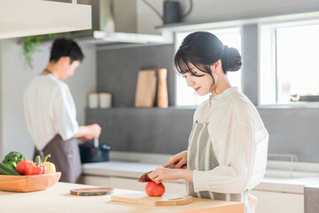 キッチンで料理・家事をする若いアジア人夫婦・カップル（包丁・切る・野菜・トマト）
 - obrazy, fototapety, plakaty