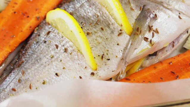 Dorado fish on baking sheet with vegetables and lemon. Seafood concept. Panning camera shot