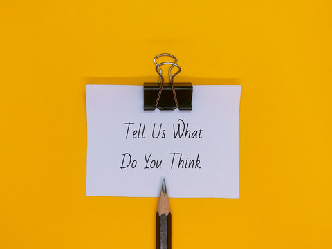 Notepad with the words "Tell Us What Do You Think" written on a yellow background.Bussiness background image concept.