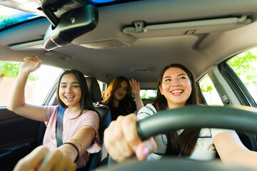 Female best friends enjoying driving listening to music