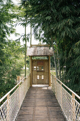 A bamboo gate at the end of a walkway on a wooden bridge.