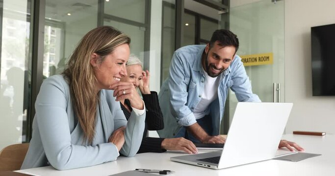 Three laughing diverse teammates using computer, discussing new on-line project, make presentation for clients, consider creative ideas, developing marketing strategy looking satisfied with teamwork