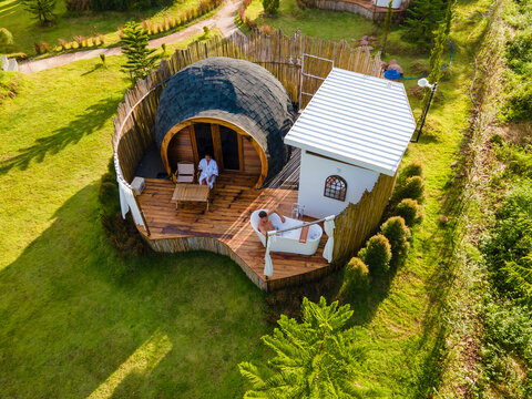 a couple of men and women camping in the mountains of Northern Thailand during vacation. Outdoor bathroom, and bathtub during sunset in the mountains at an igloo hut. drone aerial view