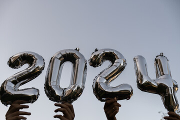 Silver foil number 2024 celebration new year balloon on blue sky background. Happy New year...