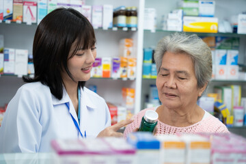 Young Asian pharmacist talking with customer at pharmacy counter. She tells customers about drug information at the pharmacy. - obrazy, fototapety, plakaty