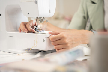 Close-up female designer sewing clothe in tailor workshop.