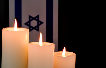 Israel flag and three different white burning candles on black background. Memorial and pray...