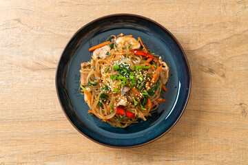 japchae or stir-fried Korean vermicelli noodles with vegetables and pork topped with white sesame