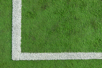 close-up image of the white line of the corner quadrant of a worn and dirty synthetic grass soccer field