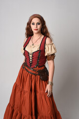 close up portrait of beautiful red haired woman wearing a medieval maiden, fortune teller costume. Posing with gestural hands reaching out, dancing, isolated on studio background.