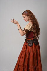 close up portrait of beautiful red haired woman wearing a medieval maiden, fortune teller costume. Posing with gestural hands reaching out, dancing, isolated on studio background.