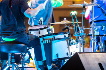 Selective focus to drum set and drummer with blurry music band in concert. - obrazy, fototapety, plakaty