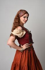 close up portrait of beautiful red haired woman wearing a medieval maiden, fortune teller costume. Posing with gestural hands reaching out, dancing, isolated on studio background.