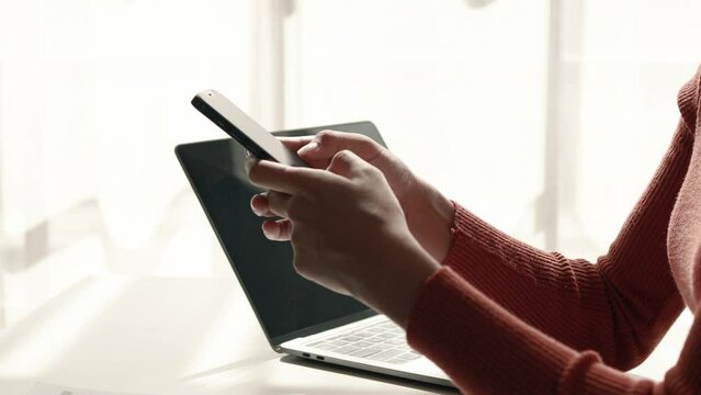 A female employee is typing a message using a smartphone app to communicate with customers who place orders on an online sales website. Concepts of using technology to communicate on smartphones.