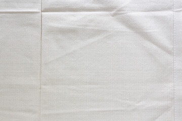 Abstract background, off white folded cotton cloth texture.