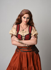 close up portrait of beautiful red haired woman wearing a medieval maiden, fortune teller costume. Posing with gestural hands reaching out, dancing, isolated on studio background.