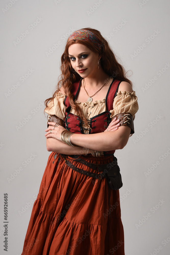 Wall mural close up portrait of beautiful red haired woman wearing a medieval maiden, fortune teller costume. Posing with gestural hands reaching out, dancing, isolated on studio background. - Wall murals