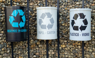 three waste cans to recycle by material, written in Spanish, in the black can general waste, in the white paper - cardboard, in the gray plastic - glass