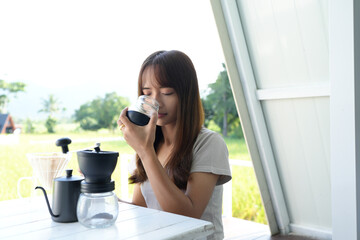 Asian female tourist Grind and brew coffee to drink in the morning.