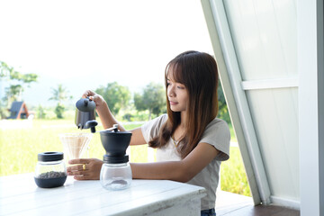 Asian female tourist Grind and brew coffee to drink in the morning.