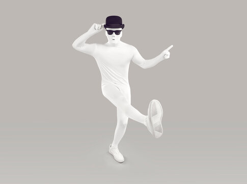 Funny disguised dancer in studio. Full length portrait of man in white bodysuit costume, mask, black bowler hat and sunglasses dancing and pointing index finger away isolated on grey color background