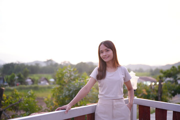 Happy Asian female tourist taking photos on the roof of her accommodation during sunset.