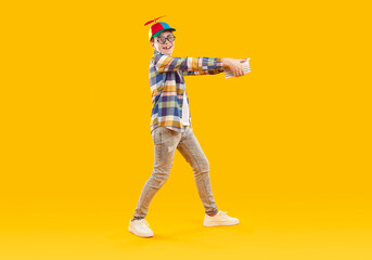 Full length portrait of a happy smiling schoolboy holding stack of books in his hands in funny...