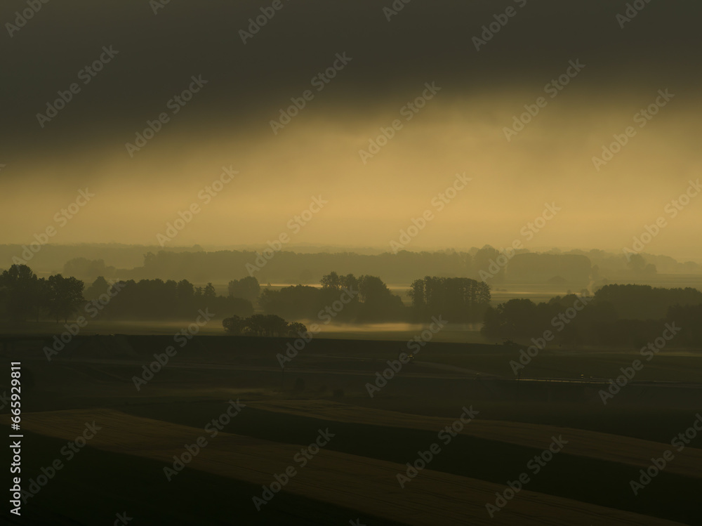 Poster riga, latvia - august 20 2023. a large field with trees in the distance under a cloudy sky.