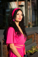 Portrait of a beautiful curly brunette in a pink dress