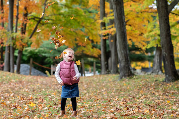 Little girl laughing while leaves are falling around her