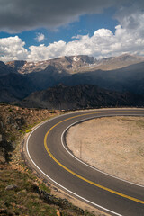 Curving alpine road with distant mountains and clouds