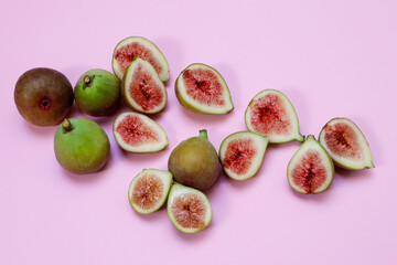 Whole and sliced figs on a pink background
