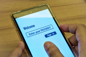 Woman using her phone with the digital display message enter your PASSKEY. Sign in page,...