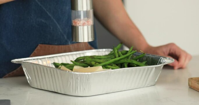 The chef salts vegetables with an electric salt shaker, manual grinder for salt