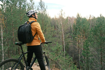 active lifestyle.A cyclist in equipment with a backpack stands with a mountain bike on a mountain and looks at the landscape.Mountain Bike