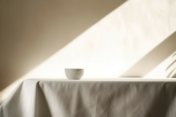 Table counter with white linen tablecloth drape in sunlight, smooth leaf shadow on wall with space in background