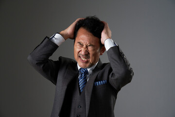 頭を抱える中年のビジネスマン　黒背景