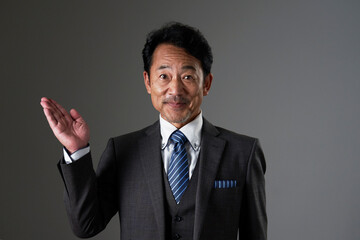 左側を手のひらで指す中年のビジネスマン　黒背景