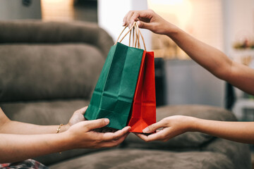 Female hand giving shopping bags in red and green color. Boxing day, sale and discount concept