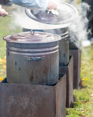 a metal pot on a fire, a soup cooker outside, cooking in the fresh air, a picnic in nature