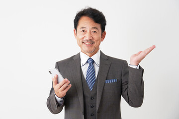 スマートフォンを持って右側を手のひらで指す中年のビジネスマン　白背景