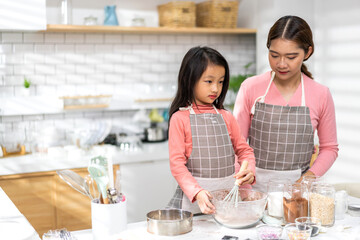 Portrait of enjoy happy love asian family mother and little toddler asian girl daughter child having fun cooking together with dough for homemade bake cookie and cake ingredient on table in kitchen