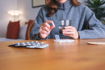 Closeup image of a woman holding pills and a glass of water