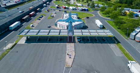 Aerial view of a highway rest area with a restaurant and large car park for cars and trucks.