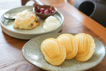 Madeleine or Madeleines and scone , cranberry scone or scone with whipped cream and berry sauce