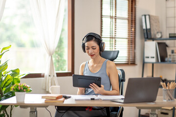 Freelancer Young business asian woman wear wireless headphone and working at home with laptop and papers on desk