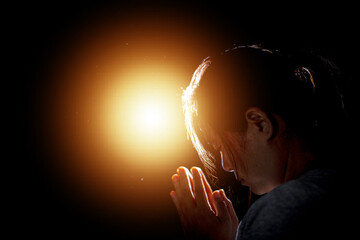 Hands folded in prayer in church. Concept for faith, spirituality and religion. Woman praying in the morning have Yellow lights and sparkles coming. Christian life crisis prayer to god. - obrazy, fototapety, plakaty