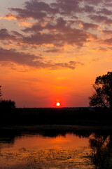 Colorful orange-red sunset over the river surface, vertical view