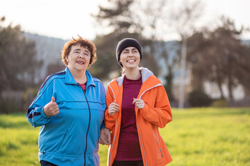 Portrait of happy mature and young women walking down the park. Spring time. International Day of Older Persons