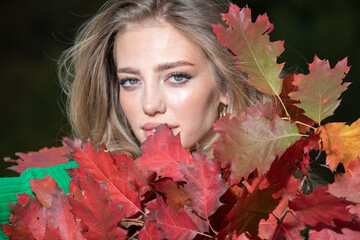 Autumn portrait of cheerful woman with yellow maple leaves. Portrait of beauty girl with autumn leafs on foliage. Close up portrait of a beautiful girl near autumn leaves. Romantic tenderness woman.